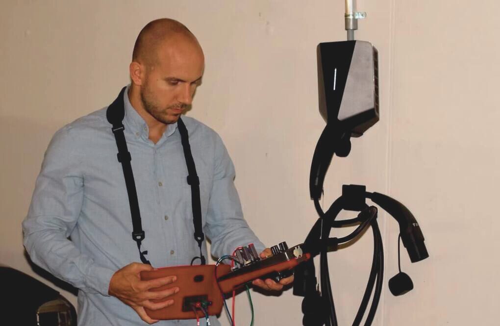 Mario Kunz prüft mit einem Messgerät eine Ladestation für Elektroautos